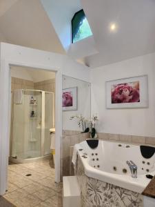 Gallery Walk Chalets - Tamborine Mountain في جبل تامبورين: حمام كبير مع حوض استحمام ودش