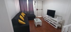 a living room with a black couch with yellow pillows at Cozzy 24 in Maputo