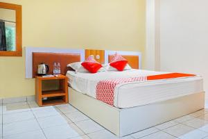 ein Schlafzimmer mit einem Bett mit roten Kissen darauf in der Unterkunft COLLECTION O 91331 Hotel Grand Saota Soppeng in Watansopeng