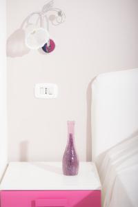 a purple bottle sitting on a nightstand next to a bed at B&B Lungomare in Naples