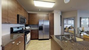 eine Küche mit einem Kühlschrank aus Edelstahl und einer Spüle in der Unterkunft Casa Marina - Modern, Stylish, Secure & Spacious Condo with 2 Master Suites in MDR & Close to Venice Beach in Los Angeles