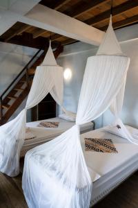 two beds in a room with white mosquito nets at Casa Nemo Beach Resort & Spa in Sabong