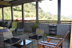 a screened in porch with chairs and a table at Au Coeur des hauts Cilaos in Cilaos