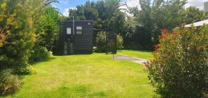 een kleine zwarte schuur in een tuin met gras bij Private Cabin in Waihi