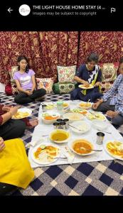 um grupo de pessoas sentadas à volta de uma mesa com comida em The Light House em Srinagar