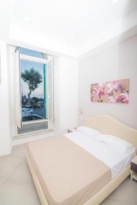 a white bedroom with a bed and a window at B&B Lungomare in Naples