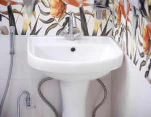 un lavandino bianco in bagno con carta da parati floreale di The Light House a Srinagar