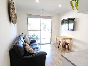 a living room with a black leather couch and a table at Seaside Aura in Victor Harbor
