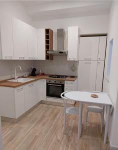 a kitchen with white cabinets and a white table at Piccolo Borgo in Ischia