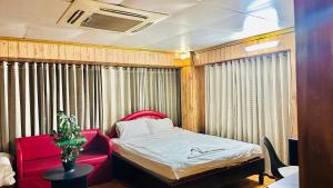 um pequeno quarto com uma cama e uma cadeira vermelha em Star Residence em Daca