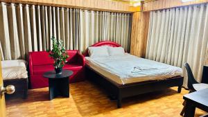 a small room with a bed and a red chair at Star Residence in Dhaka