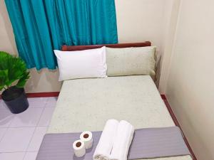 um pequeno quarto com uma cama com toalhas em #1 Green Room Inn Siargao em General Luna