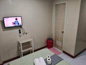 #1 Green Room Inn Siargao في جنرال لونا: غرفة مع تلفزيون على الحائط وكرسي احمر