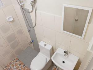 a bathroom with a white toilet and a sink at #1 Green Room Inn Siargao in General Luna