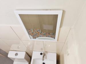 a bathroom with a toilet and a sink and a mirror at #1 Green Room Inn Siargao in General Luna
