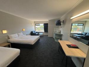 a hotel room with two beds and a desk at Geraldton Motor Inn in Geraldton