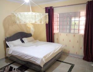 - une chambre avec un lit et un lustre dans l'établissement Roma Stays- Modern and stylish Two-bedroom apartment in Busia (near Weighbridge), à Busia