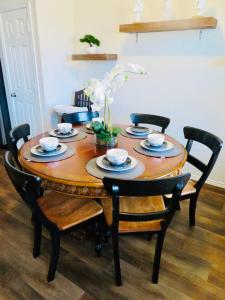 a wooden table with chairs and plates and flowers on it at New House family friendly near Six Flags Sea World in Helotes