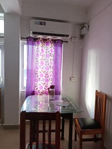 a dining room table with a window with purple curtains at Punjab Residency in Port Blair