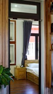 a bedroom with a bed and a window and a mirror at HUNA House in Da Lat