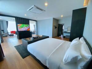 a bedroom with a large white bed and a living room at BB hotel Savannakhet in Savannakhet
