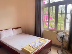 una camera con letto, ventilatore e finestra di Hải Yến Hotel Quảng Bình a Dong Hoi