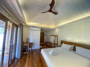 um quarto com uma cama branca e uma ventoinha de tecto em Nongkhiaw The Float House em Nongkhiaw