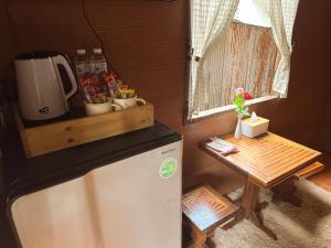 a small kitchen with a refrigerator and a table at บ้านพักกึ๊ดเติง แม่กำปอง เชียงใหม่ in Mae On