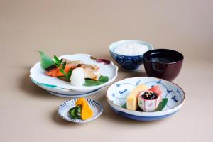 uma mesa com pratos de comida e tigelas de arroz em 砂川パークホテル em Sunagawa