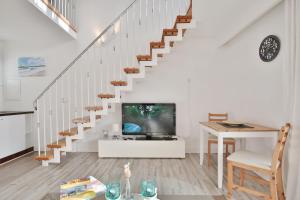 a living room with a tv and a staircase at Haus Miramar Treffert Appartement 21 in Niendorf