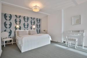 a white bedroom with a white bed and a wall at Haus Miramar Treffert Appartement 21 in Niendorf +19 photos