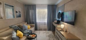 Lux Home Astana في أوست - كامينوغورسك: غرفة معيشة مع أريكة وتلفزيون بشاشة مسطحة
