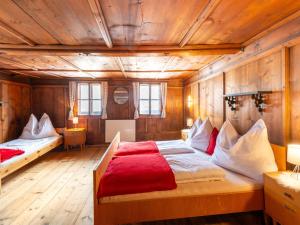 a bedroom with wooden walls and a bed with red sheets at Quaint farmhouse in Bramberg am Wildkogel in Neukirchen am Großvenediger