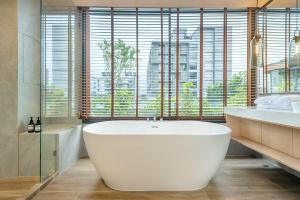 een badkamer met een wit bad en een groot raam bij Salaya One Hotel & Service Apartment in Salaya