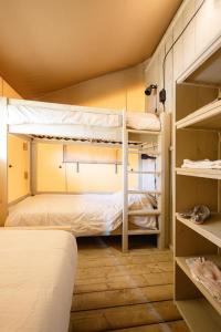 2 Etagenbetten in einem Zimmer mit Regalen in der Unterkunft Glampingzelt Family - Lodge in Soltau