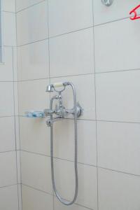 a shower with a hose in a white tiled bathroom at Winmond Hotel in Wakiso