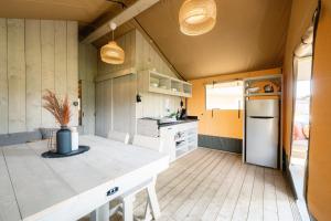 a kitchen with yellow walls and a white refrigerator at Glampingzelt Family - Lodge in Soltau