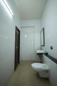 a white bathroom with a toilet and a sink at Hotel Saishree` in Shirdi