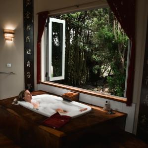 Una chica en una bañera con ventana en Eagles Nest Retreat en West Kentish