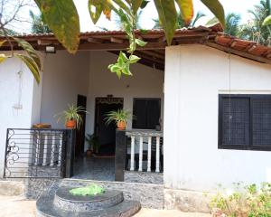 a white house with a gate and potted plants at Tulsi Authentic Homestay - Beach Village Goa in Canacona