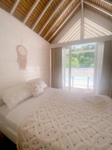 a white bed in a room with a window at Love Coconut Bungalow in Gili Trawangan