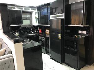 uma cozinha preta com electrodomésticos pretos e um sofá em بورتوسعيد em `Ezbet Shalabi el-Rûdi