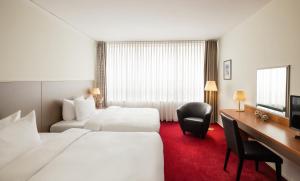 a hotel room with two beds and a desk at Lindner Hotel Cottbus in Cottbus