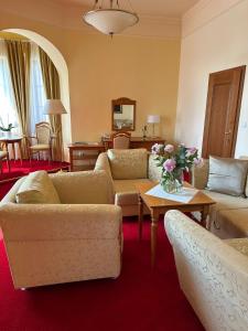 a living room with couches and a table with flowers at Hotel Slunce in Uherské Hradiště