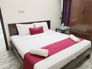 ARL Home Stay, Porur في تشيناي: غرفة نوم بسرير ابيض كبير ومخدة حمراء