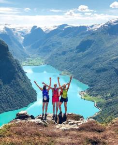 three women standing on top of a mountain with their arms up at Flo Bellevue in Stryn