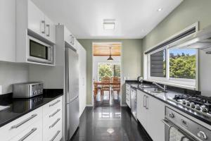 a kitchen with white cabinets and a large window at Bay Vista Retreat in Pohara