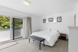 a white bedroom with a bed and a window at Bay Vista Retreat in Pohara