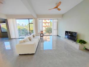 a living room with a white couch and a ceiling fan at shadow climers guest house in Yangshuo