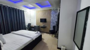 um quarto de hotel com uma cama e um tecto azul em Weltons Apartments em Ikeja
